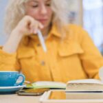 woman holding a pen while drinking coffee and reading-How to start intermittent fasting