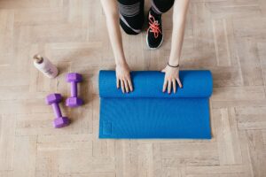 hands rolling exercise mat next to free weights-workout at home