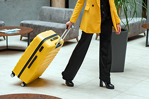 woman in yellow jacket pulling a yellow suitcase